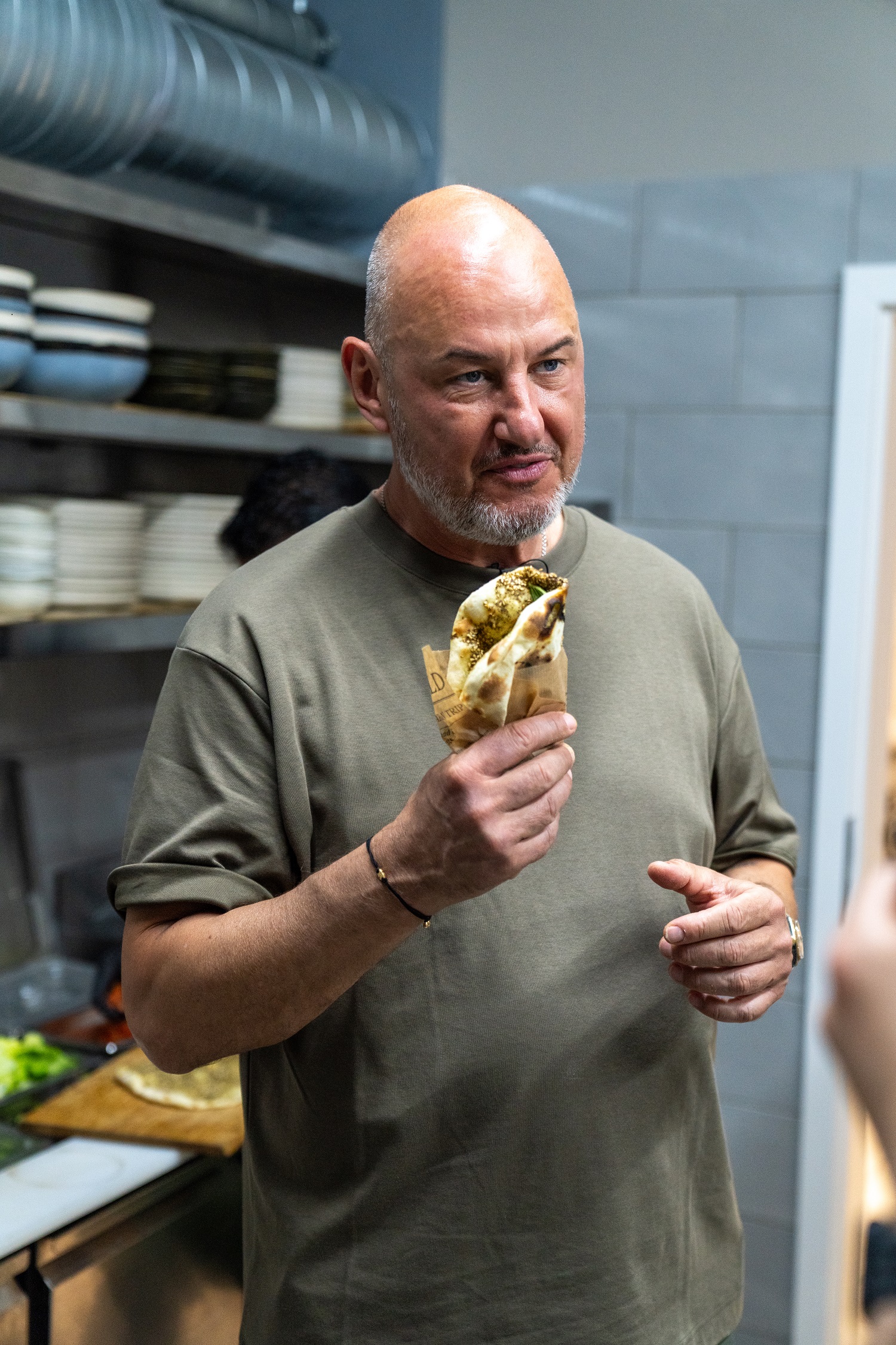 Sternekoch Frank Rosin steht in der Küche des Restaurants "M'Oregano" und hält Man'oushe in der Hand, die er gerade zusammen mit Mo zubereitet hat.
