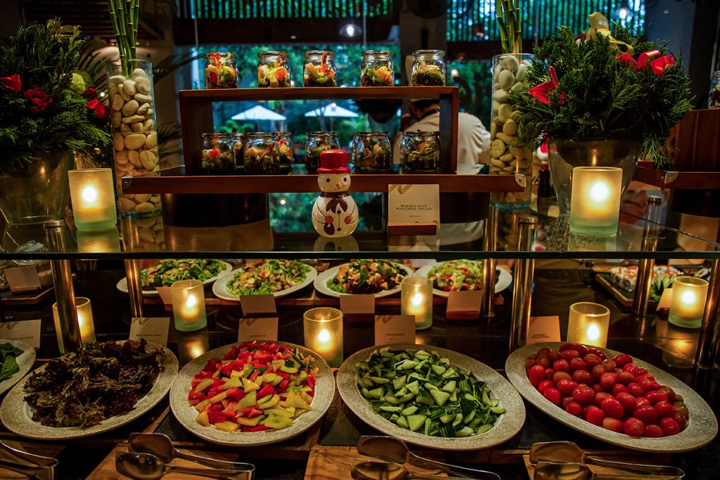 Weihnachtsfeier Catering in einem Restaurant: An einem Buffet sind verschiedene Gerichte, hauptsächlich Salate, zu sehen, ebenso wie festliche Dekoration.