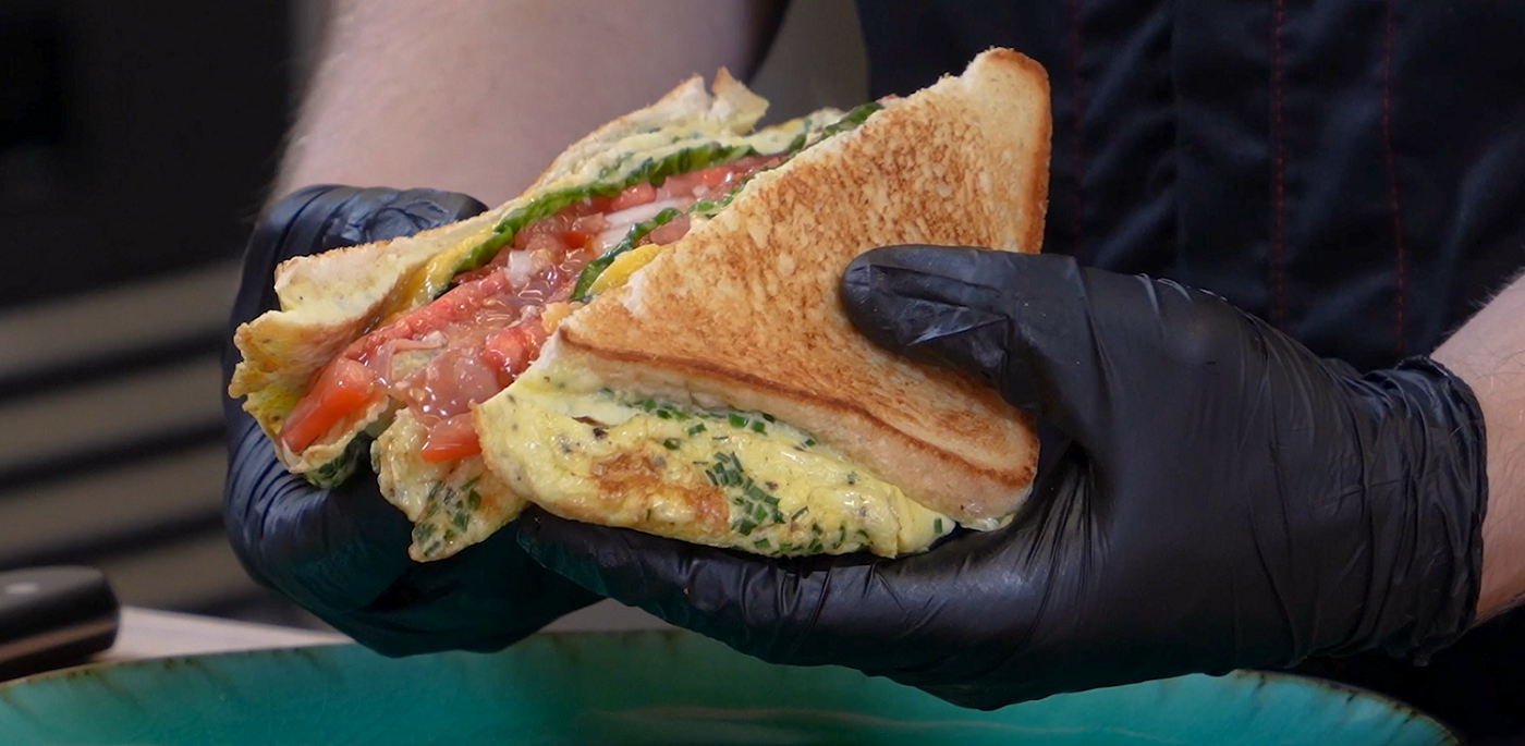 Auf dem Bild sieht man ein in der Hälfte durchgeschnittenes Omelette Sandwich.