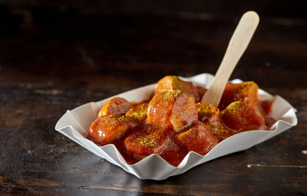 Currywurst mit Pommesgabel aus Holz in der klassischen Pappschale